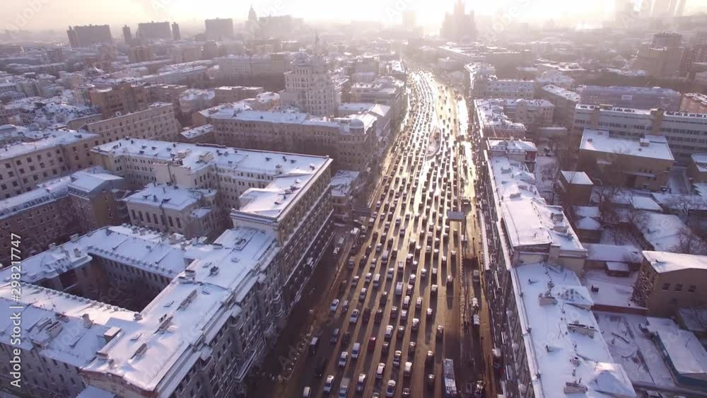 Wide road traffic winter frozen Moscow aerial flight above city center. Bright sun white snow on roofs cold weather. Historical old historical soviet buildings. Logistics travel. Cinematic 