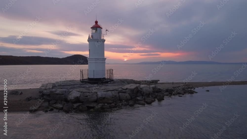 Beautiful lighthouse Vladvostok on sand bar. Romantic purple sunset clouds Seagulls fly by Calm Ocean Sea. Russia Far east. Navigation happiness peace of mind. Aerial Drone flying forward Beautiful lighthouse Vladvostok on sand bar. Romantic purple sunset clouds Seagulls fly by Calm Ocean Sea. Russia Far east. Navigation happiness peace of mind. Aerial Drone flying forward