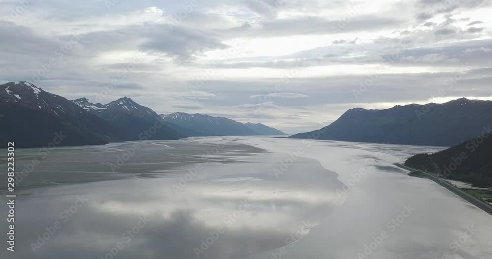 Aerial shot flying slowly backwards over the calm waters of the Cook Inlet in South-Central Alaska. Tall, Majestic Alaskan mountains can be seen on both sides of the inlet. Aerial shot flying slowly backwards over the calm waters of the Cook Inlet in South-Central Alaska. Tall, Majestic Alaskan mountains can be seen on both sides of the inlet.