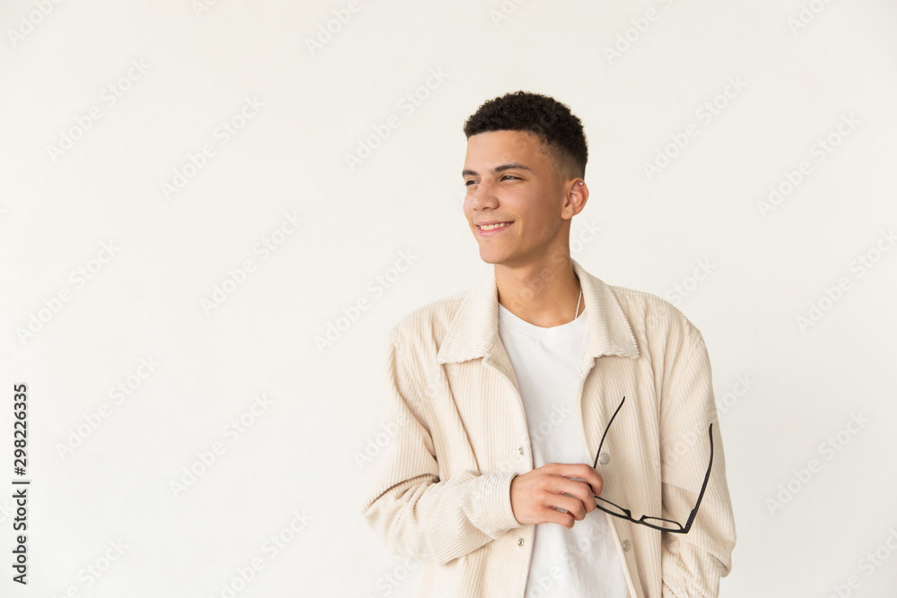 Content young man holding eyeglasses. Portrait of handsome happy man holding spectacles and looking aside isolated on grey background. Eyewear concept Content young man holding eyeglasses. Portrait of handsome happy man holding spectacles and looking aside isolated on grey background. Eyewear concept