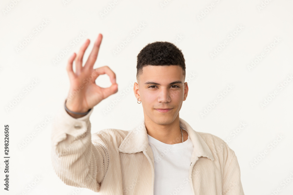 Confident man showing ok sign. Portrait of handsome serious young man showing ok symbol with hand and looking at camera. Gesture concept Confident man showing ok sign. Portrait of handsome serious young man showing ok symbol with hand and looking at camera. Gesture concept