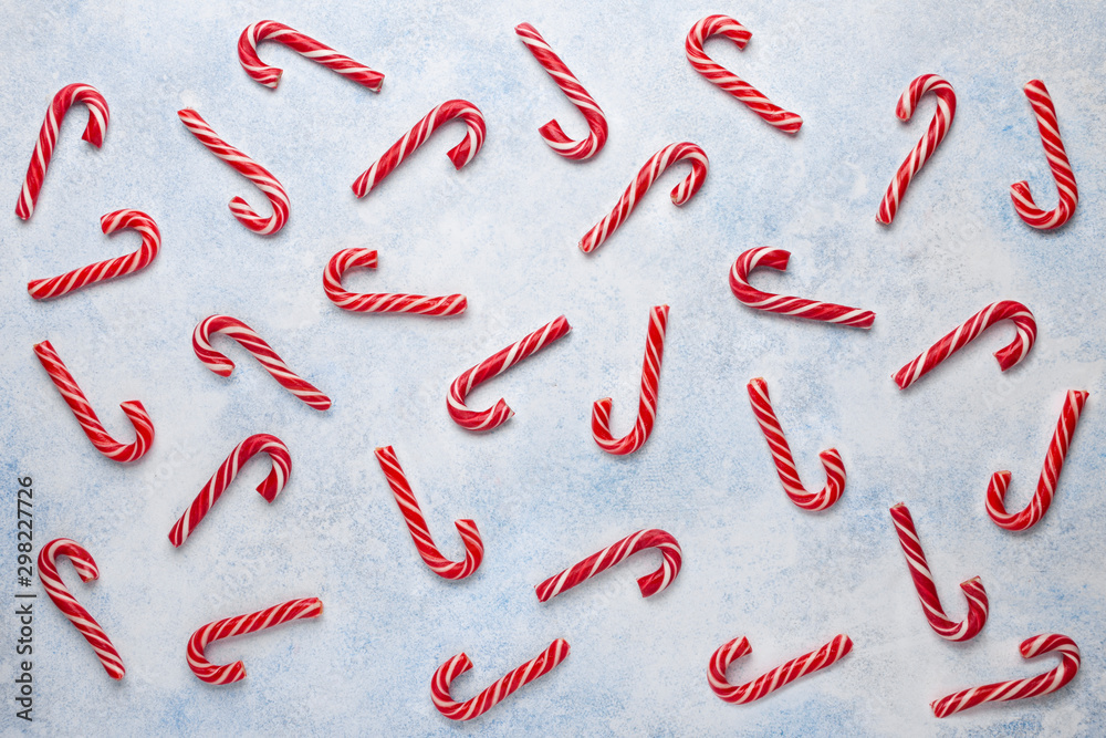 Christmas pattern made of candy canes on blue backgrond. Flat lay, top view. Christmas pattern made of candy canes on blue backgrond. Flat lay, top view.