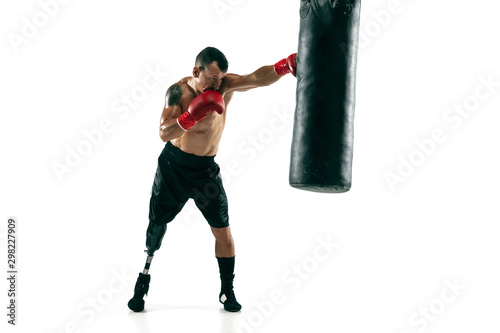 Full length portrait of muscular sportsman with prosthetic leg, copy space. Male boxer in red gloves training and practicing. Isolated on white studio background. Concept of sport, healthy lifestyle. © master1305