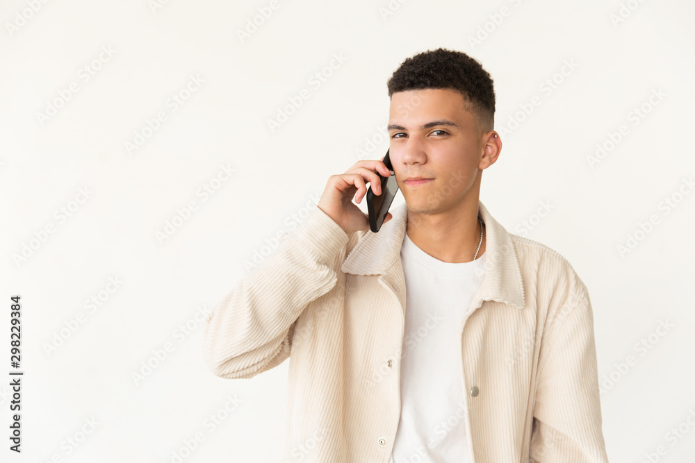 Serious young man talking by smartphone. Portrait of confident focused young man talking by cell phone and looking at camera. Communication concept Serious young man talking by smartphone. Portrait of confident focused young man talking by cell phone and looking at camera. Communication concept