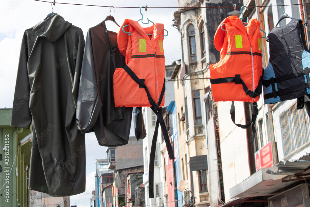 Raincoat and life jacket hanging from above. Hanged in front of the store.