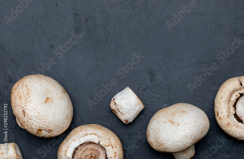 Freshly sliced mushrooms (mushrooms, cut foot, Bisporus agaricus) raw (uncooked). Black slate background. Space to include texts (copy space)