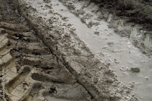 Traces de pneus dans la boue d'un chemin de terre.