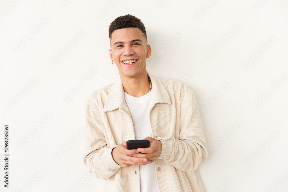 Cheerful young man holding cell phone. Portrait of handsome happy young man holding smartphone and looking at camera on grey background. Technology concept Cheerful young man holding cell phone. Portrait of handsome happy young man holding smartphone and looking at camera on grey background. Technology concept