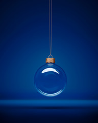 Glass christmas bauble hanging in front of luxury dark blue background.