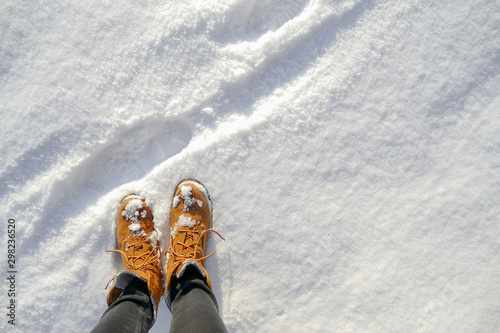 Top view of yellow shoes / boots footprint in fresh snow. Winter season.