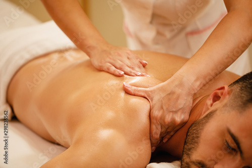 Relaxed man enjoying in back massage at health spa.