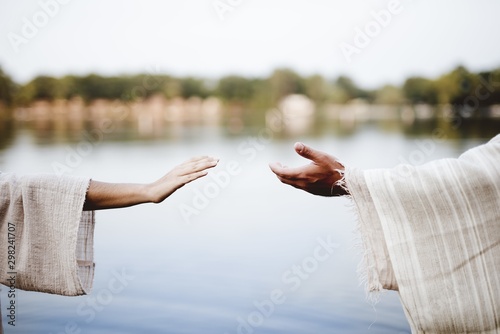 Foto Biblical scene - of a female grabbing the hand of Jesus Chris with a blurred bac