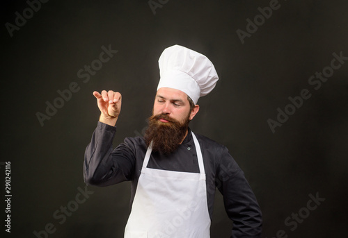 Handsome bearded chef in uniform spilling salt. Man chef in restaurant kitchen preparing food adding salt. Male chef sprinkling salt Bae. Cook man sprinkling salt. Ingredients. Professional kitchen. photo