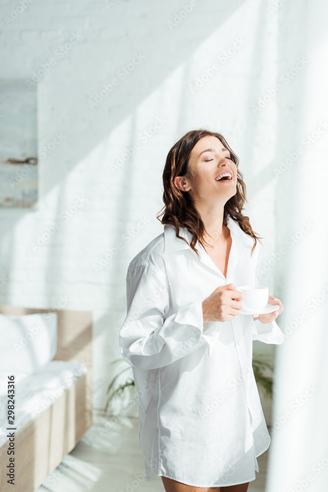 attractive woman in white shirt smiling and holding cup at morning attractive woman in white shirt smiling and holding cup at morning