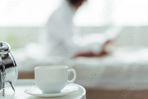 selective focus of cup of coffee and saucer in bedroom at morning