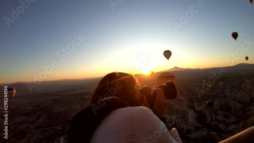 Girl taking pictures in hot air balloon at sunrise, Cappadocia, Turkey photo