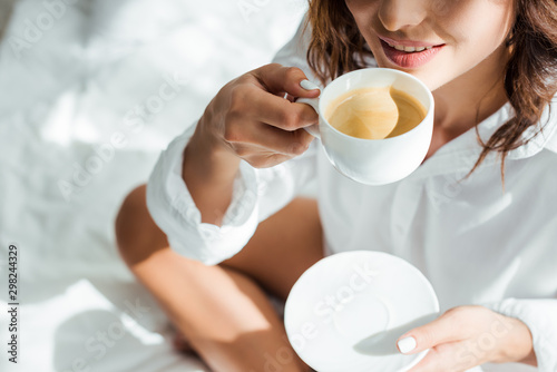 cropped view of woman drinking coffee from cup at morning photo
