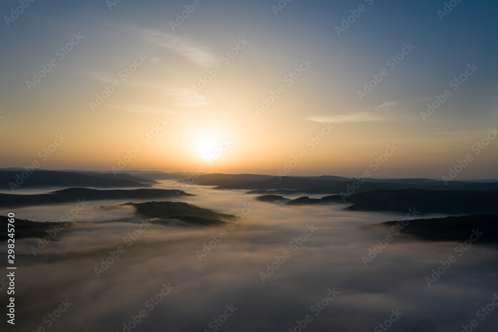 Misty sunrise with sunrays over the hills in Transylvania, Romania.