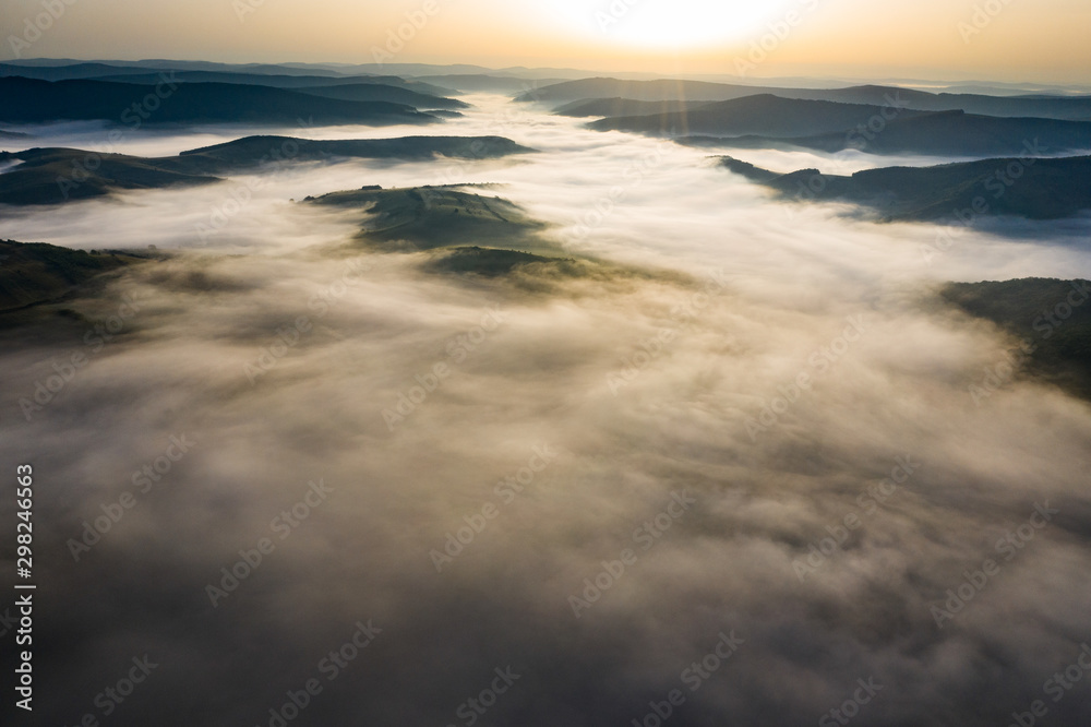 Misty sunrise with sunrays over the hills in Transylvania, Romania.