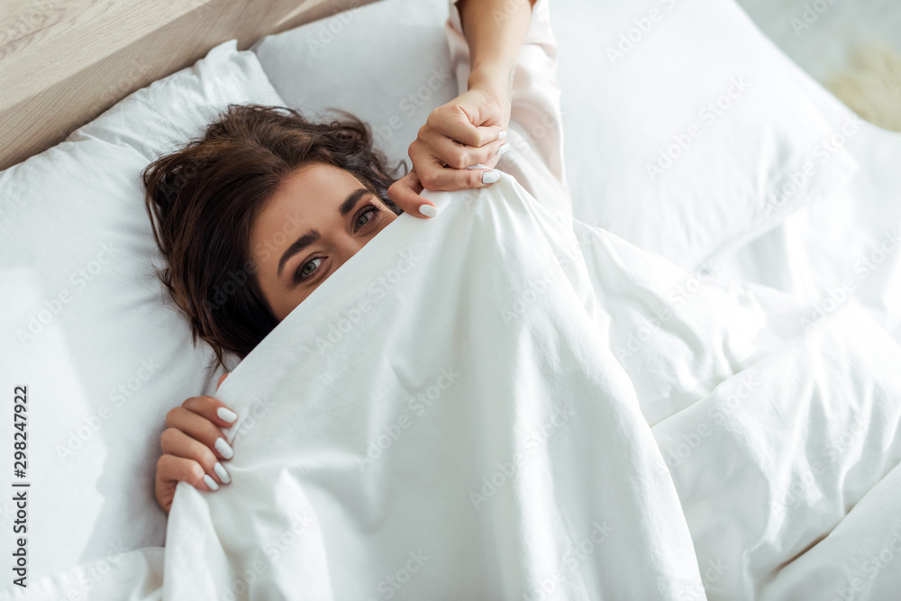 attractive woman obscuring her face with blanket at morning attractive woman obscuring her face with blanket at morning