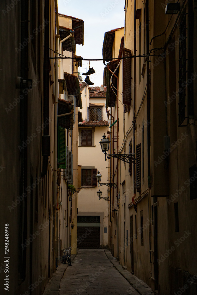 Florence narrow street with a pair of shoes hanging  on a wire. shoe tossing.