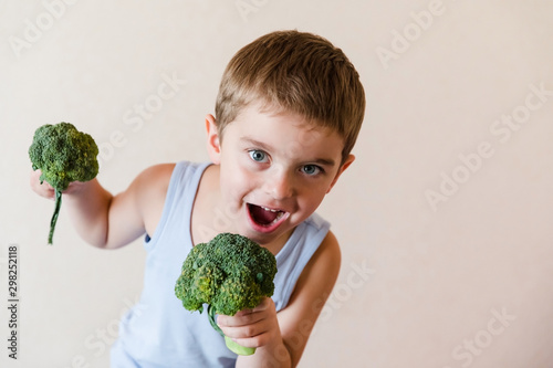 Healthy food, green broccoli vegetables in the hands of a cheerful boy child