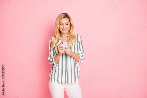 Photo of cheerful positive cute nice attractive mature woman wearing white trousers pants smiling toothily browsing through telephone isolated pastel color background