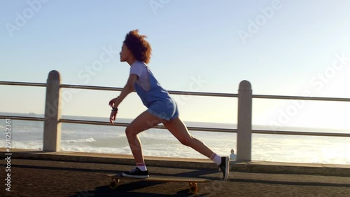 Girl longboarding riding skating enjoying sunshine and being by the ocean photo