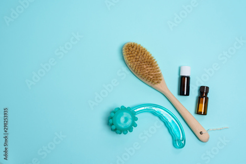 Anti-cellulite dry body massage brush  aromatherapy oil  massager on blue background. Lymphatic drainage body massage. close up