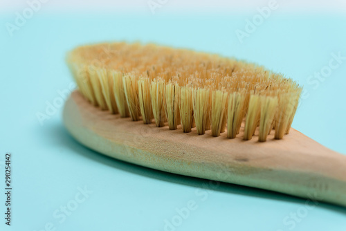 massage wooden soft body brush with natural pile  on a blue background  used in dry body massage in problem areas