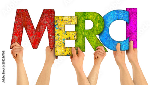 people holding up colorful rainbow wooden letter with the french word Merci (english traslation: thank you) isolated white background. grateful happy love concept. photo