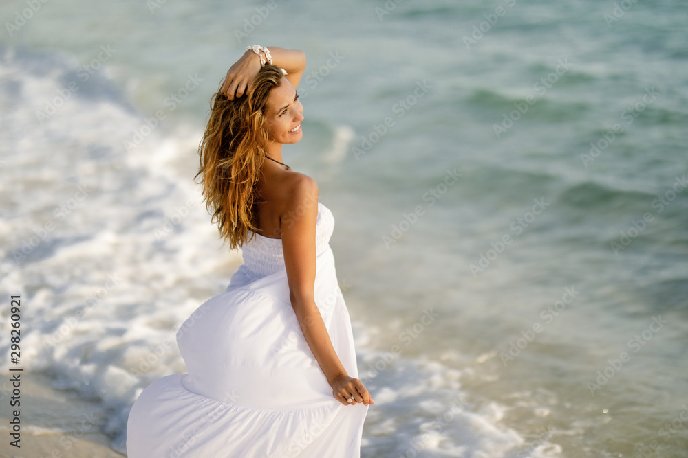 Beautiful woman in white dress at the shore during summer day. Beautiful woman in white dress at the shore during summer day.