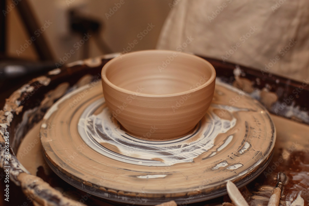 A raw clay plate stands on a potter's wheel in a pottery workshop class.Art, creativity. A raw clay plate stands on a potter's wheel in a pottery workshop class.Art, creativity.