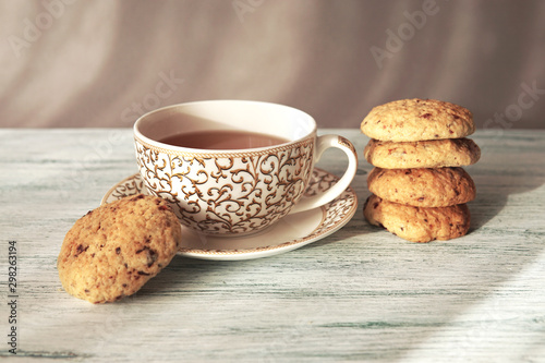 Freshly baked homemade biscuits with cup of tea on plate. Beautiful daylight and shadows. Light gray background.