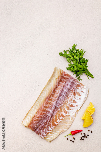 Raw pollock (Pollachius virens) fillet. Fresh fish for healthy food lifestyle. Lemon, parsley, sea salt, chili, black peppercorn photo