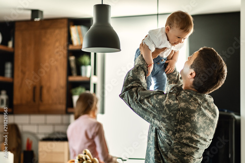 Playful military man having fun with his small son at home.