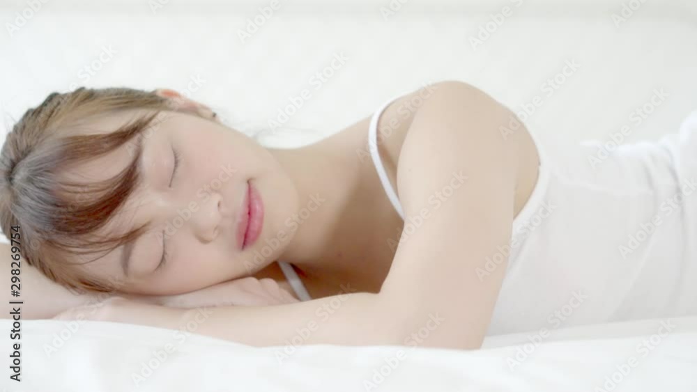 Beautiful asian young woman sleeping lying in bed with head on pillow comfortable and happy in the bedroom moving panning camera. girl with relax and leisure for health concept, slow motion. Beautiful asian young woman sleeping lying in bed with head on pillow comfortable and happy in the bedroom moving panning camera. girl with relax and leisure for health concept, slow motion.