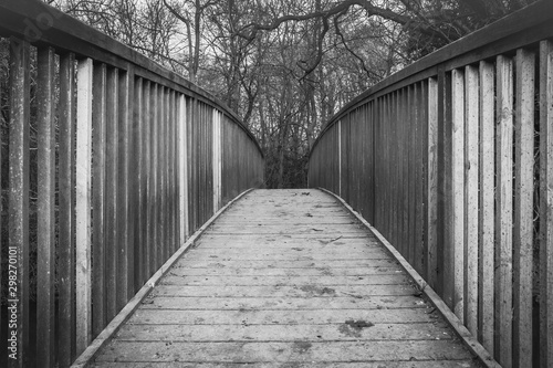 Abstract view of a timber-built footbridge showing detail of the design and construction. Spanning an inland river, the bridge is located in a forest clearing within the UK.