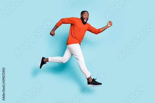 Photo of cheerful positive excited crazy running jumping black man wearing sneakers white trousers pants aspiring for sales isolated vivid blue color background
