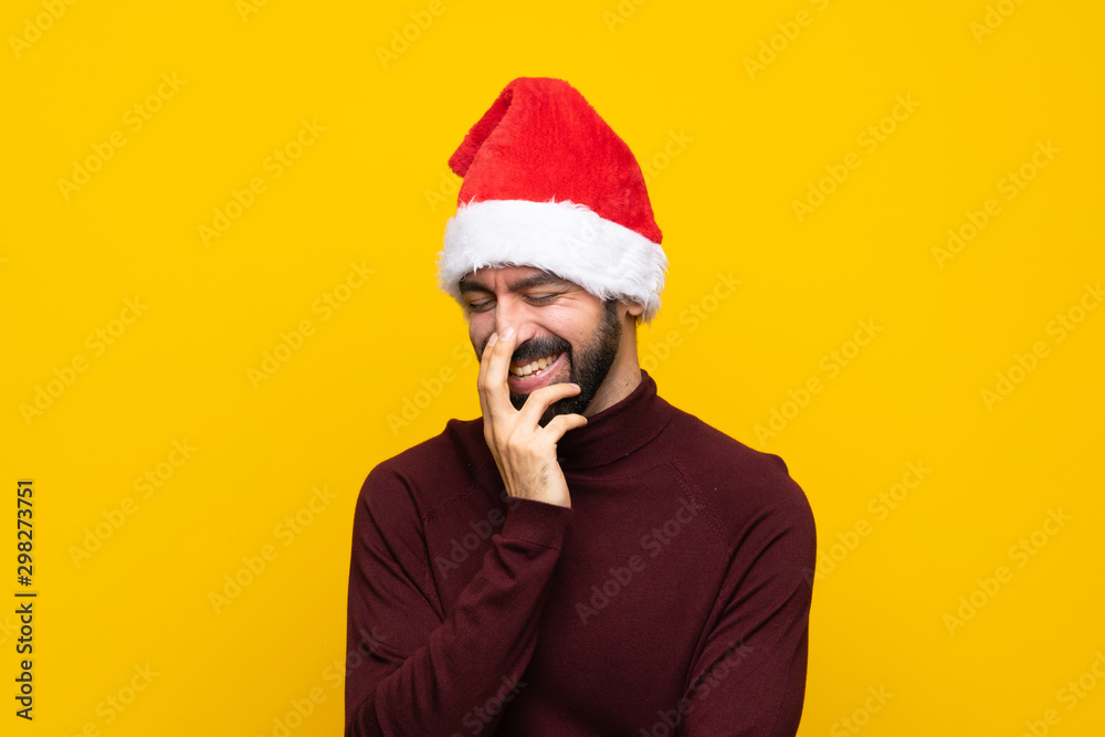 Man with christmas hat over isolated yellow background smiling a lot Man with christmas hat over isolated yellow background smiling a lot