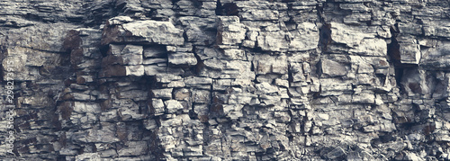 Fotografie, Obraz Dangerous vertical wall with protruding crumbling layered wild stone blocks