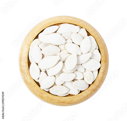Dired pumpkin seeds with shell on wooden dish.