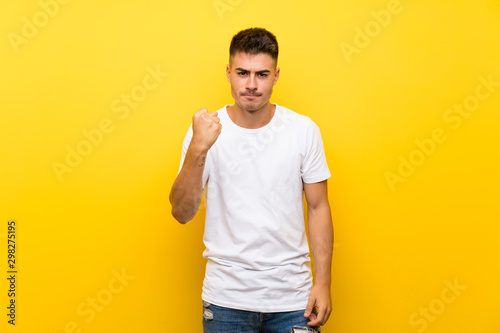 Young handsome man over isolated yellow background with angry gesture