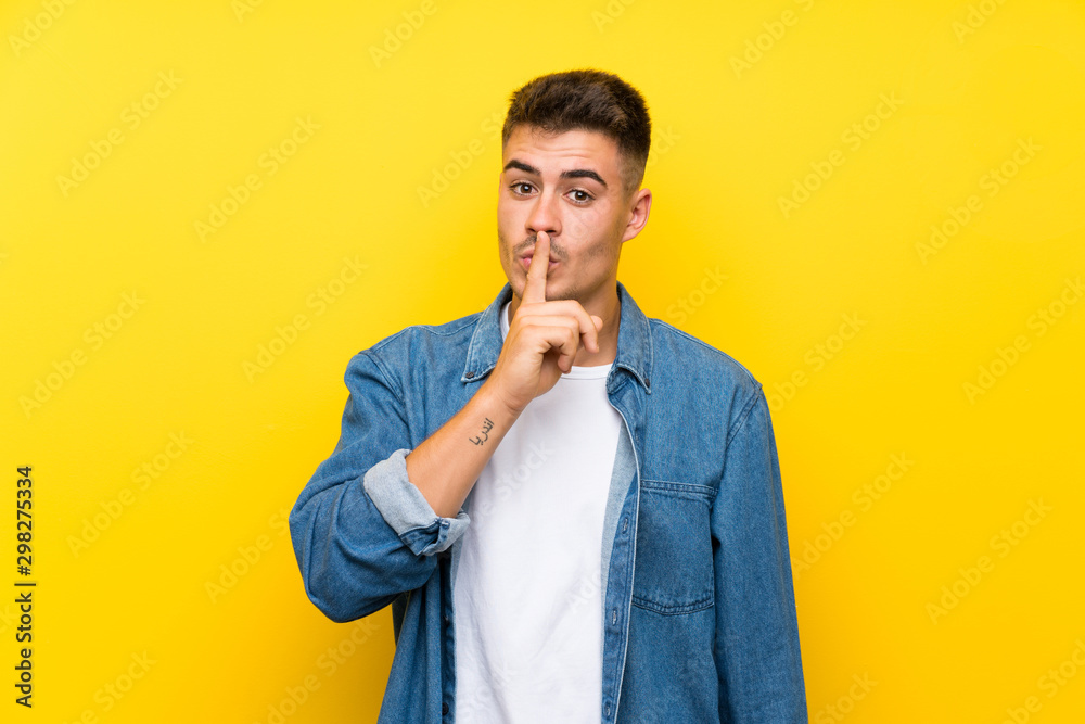 Young handsome man over isolated yellow background doing silence gesture Young handsome man over isolated yellow background doing silence gesture