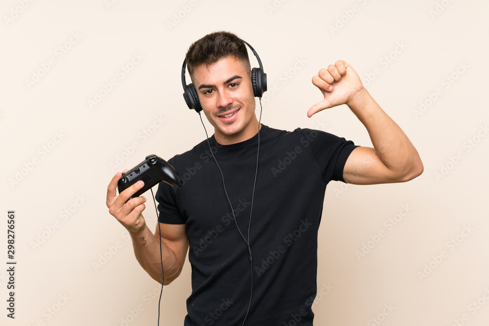 Young handsome man playing with a video game controller over isolated background proud and self-satisfied Young handsome man playing with a video game controller over isolated background proud and self-satisfied