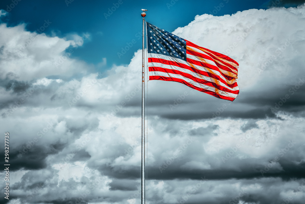 Star-striped American flag flutters proudly against the blue sky. Star-striped American flag flutters proudly against the blue sky.