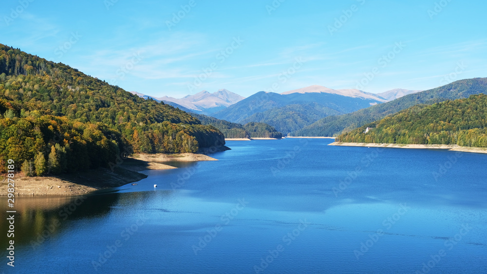 Lake Vidraru seen from Vidraru Dam, Arges county, Romania, with Fagaras mountain peaks in the distance, on a clear, sunny Autumn day.