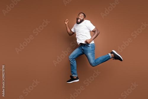 Full length body size view of his he nice attractive cheerful cheery funky childish bearded guy jumping having fun running fooling isolated on dark red brown pastel color background