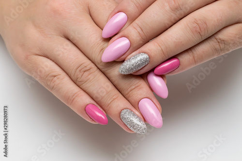 Manicure. Pink  dark pink manicure on long sharp notes with silver sparkles close-up on a white background.