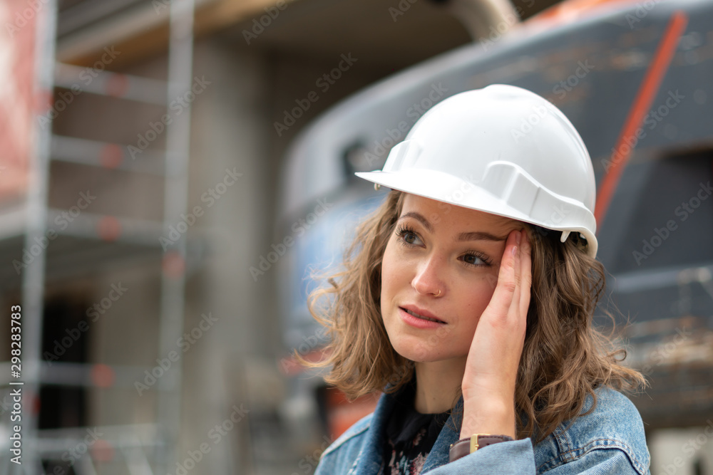 Tired factory female employee rubbing her temples dealing with an awful migraine headache Tired factory female employee rubbing her temples dealing with an awful migraine headache